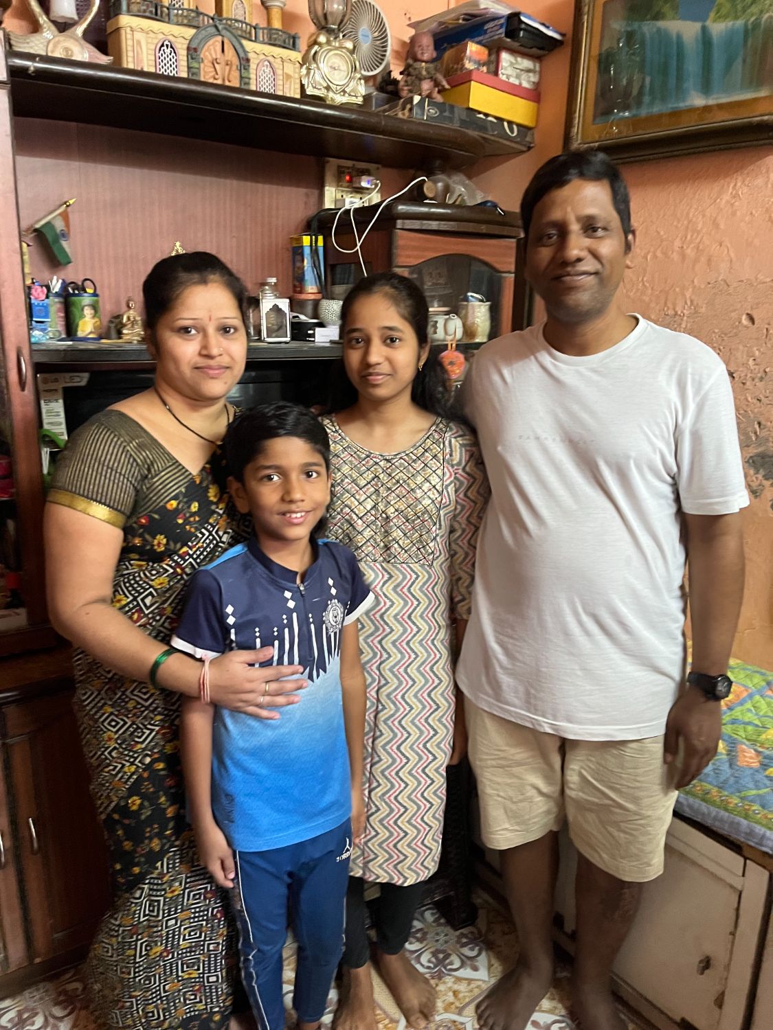 A woman stands with her family outside their home.