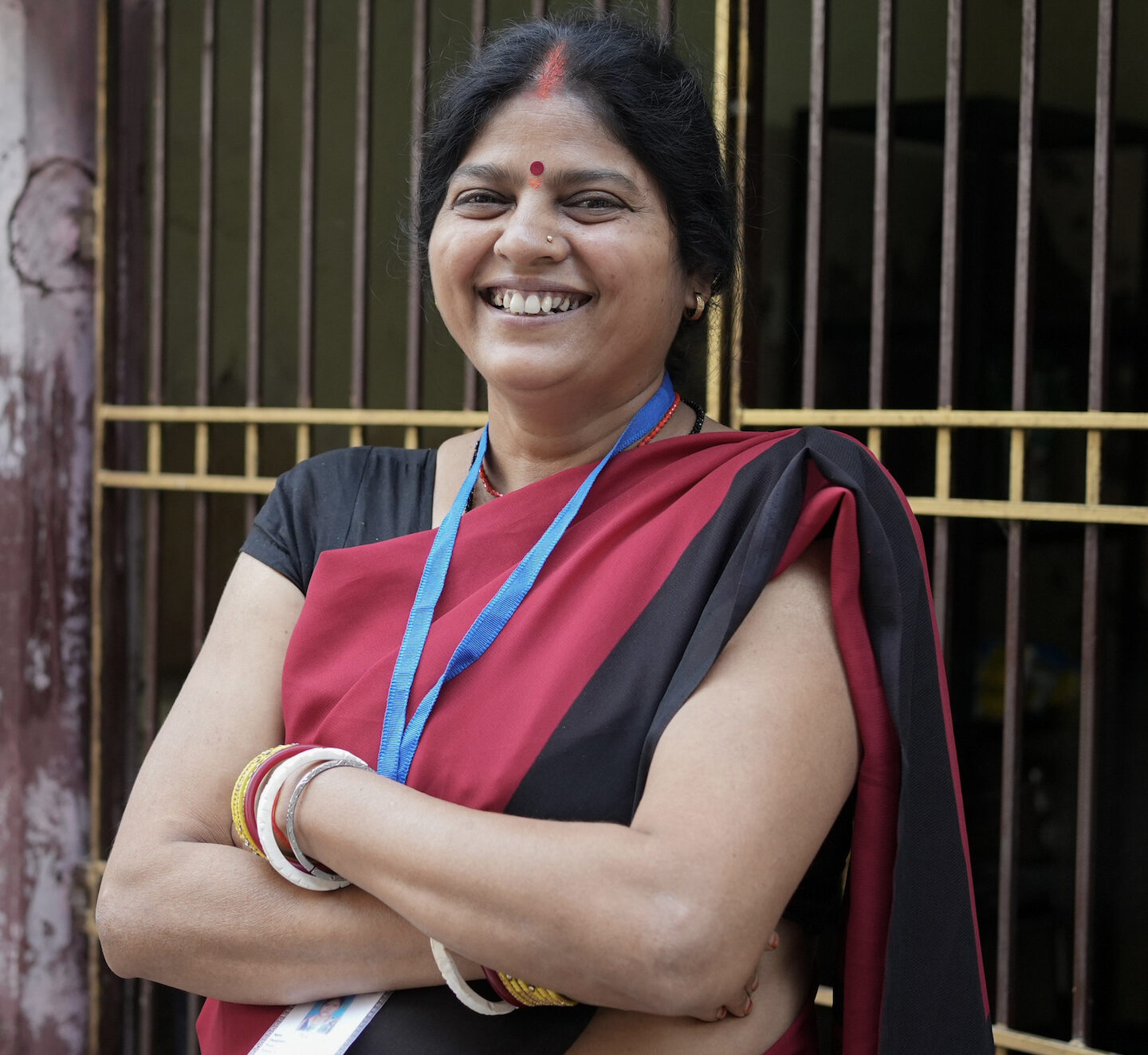 A Health Leader stands at the entrance to her community, wearing her program identification.