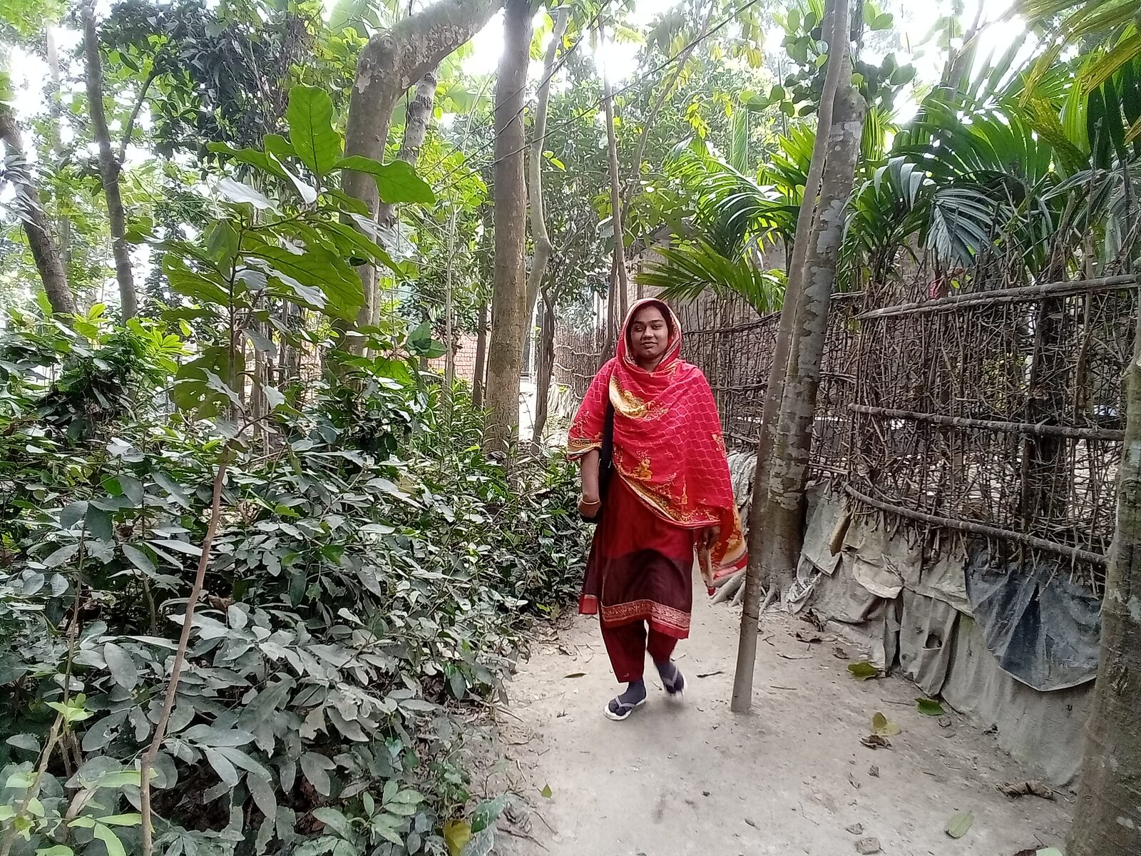 A Health Leader walks a path between homes on her way to visit families in her community.