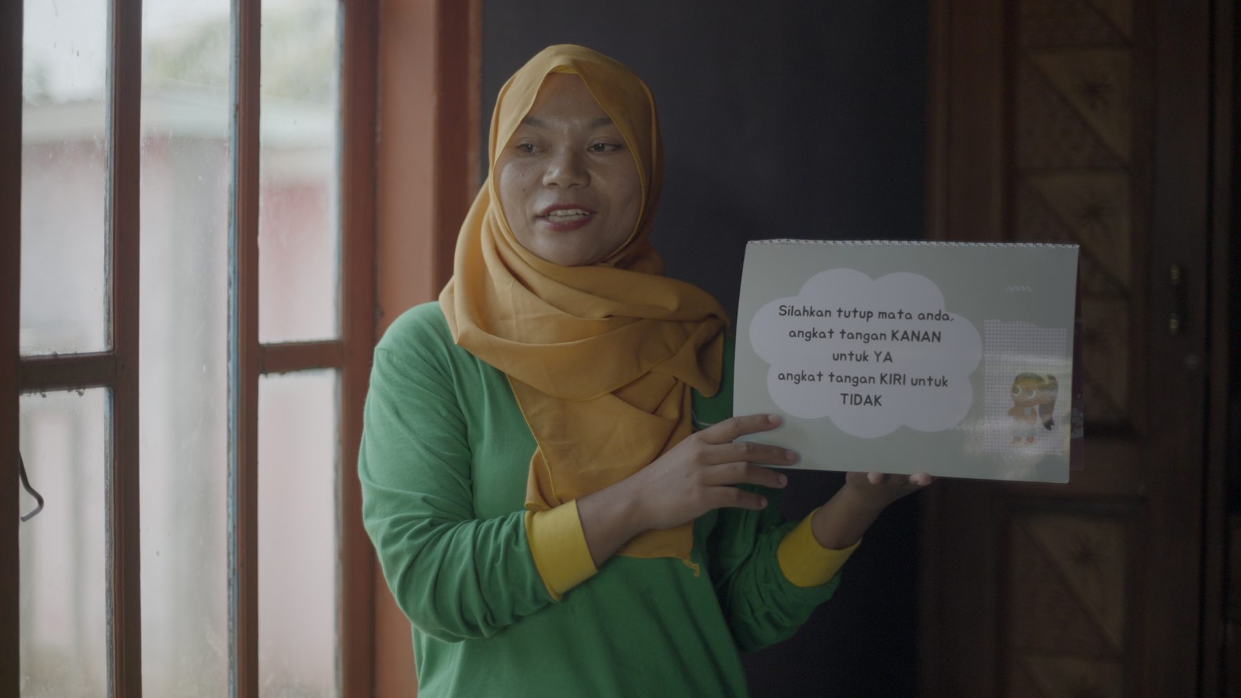 A Health Leader in Indonesia holds up a flip chart as she delivers a health education session.