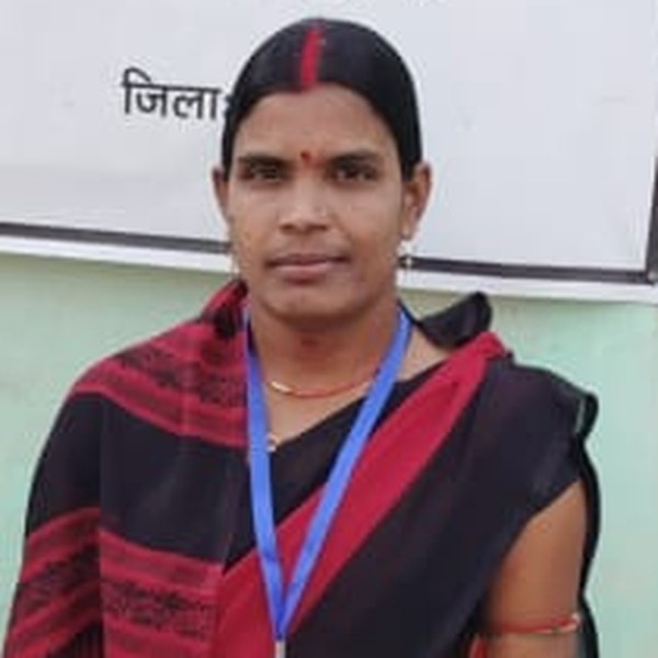 A Health Leader stands outside a health consultation point, wearing her programme identification.